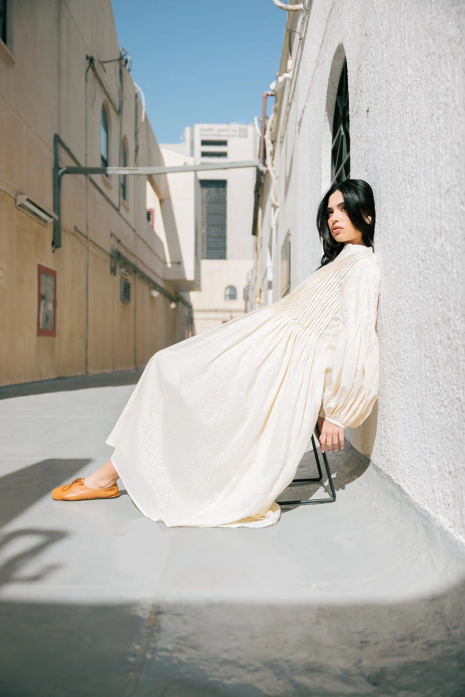 Model in an abaya posing against white walls in Kuwait