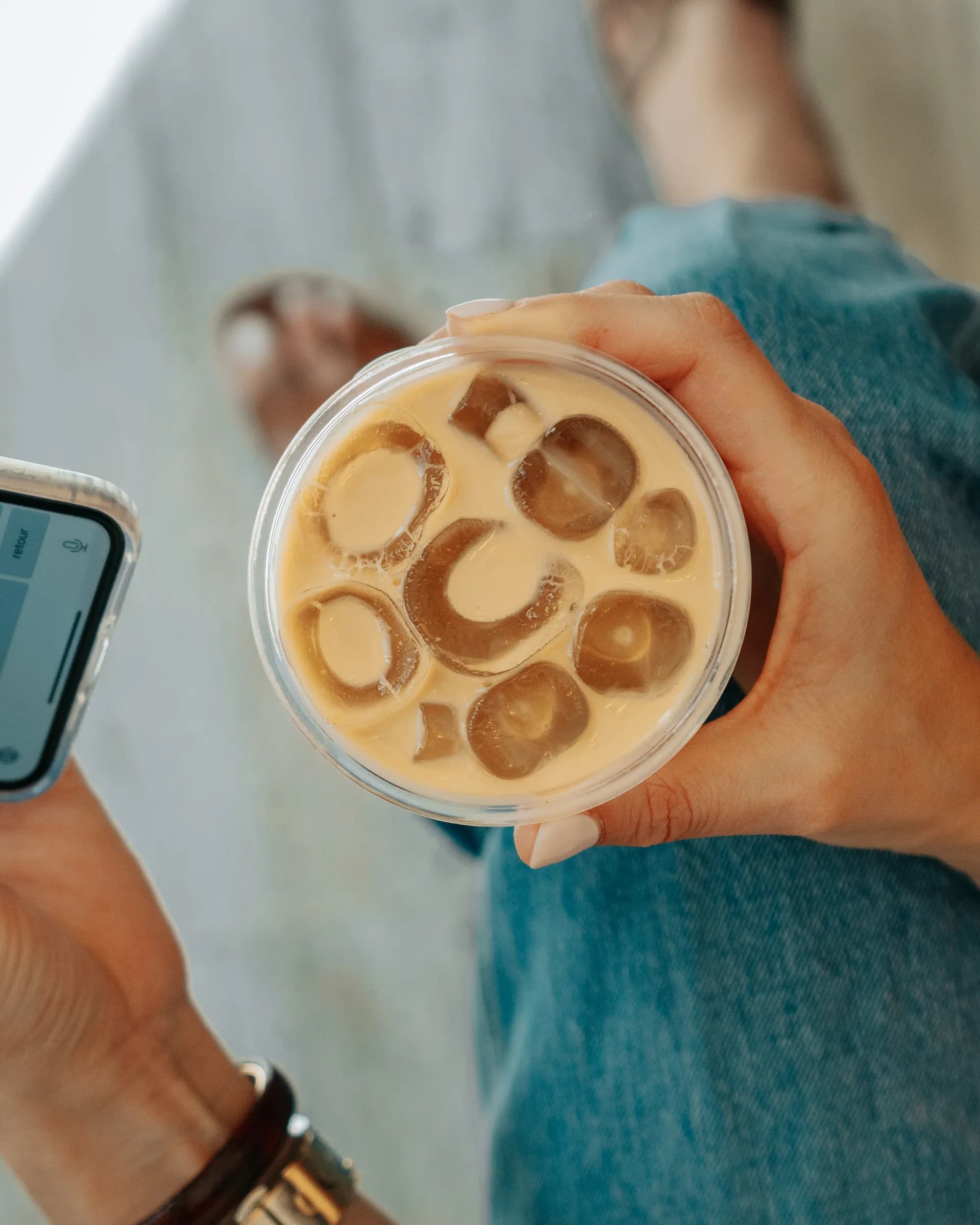 Iced latte held over denim from above