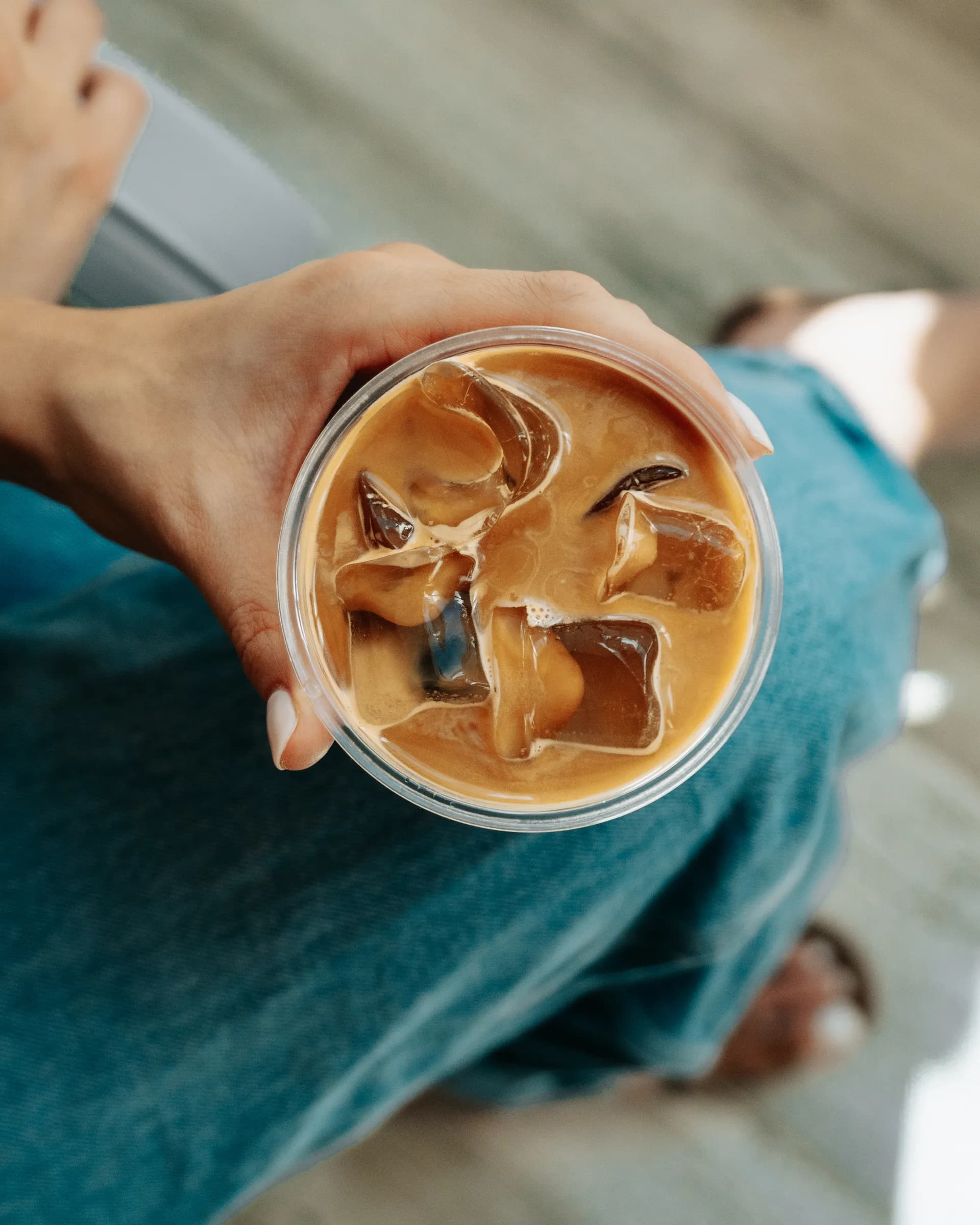 Iced latte held over denim from above