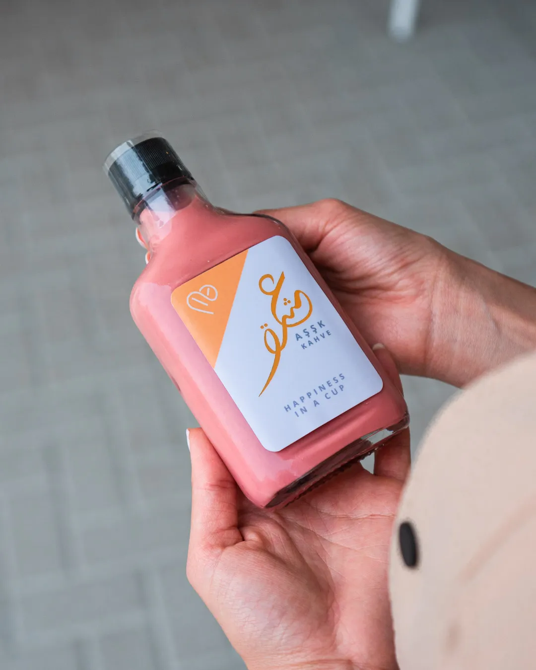 Hand holding a bottled drink in front of pink bougainvillea