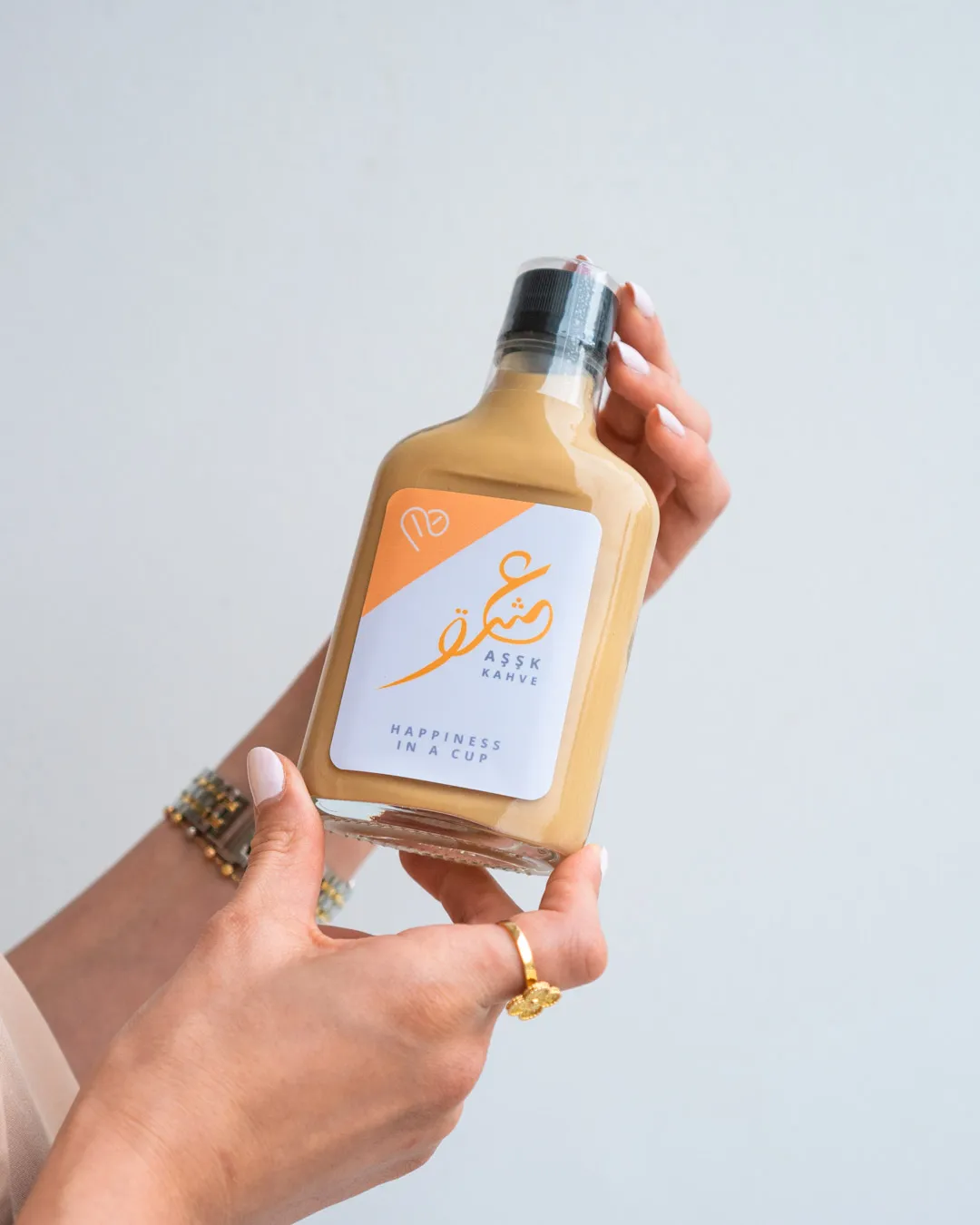 Hand holding a bottled drink in front of pink bougainvillea